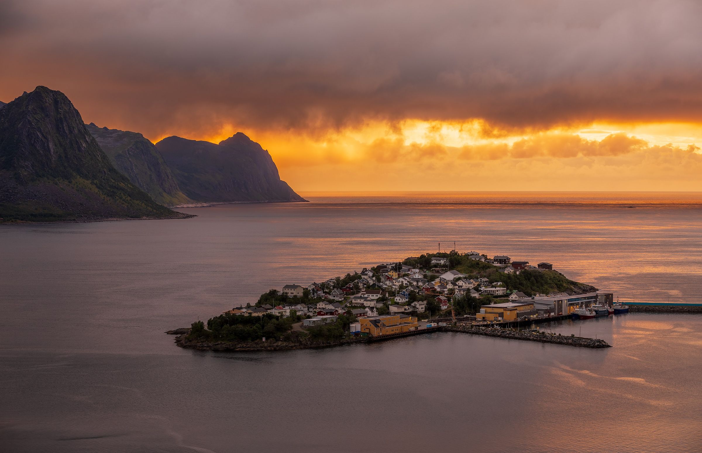 Fjord og fjell ved solnedgang med et kompass i forgrunnen