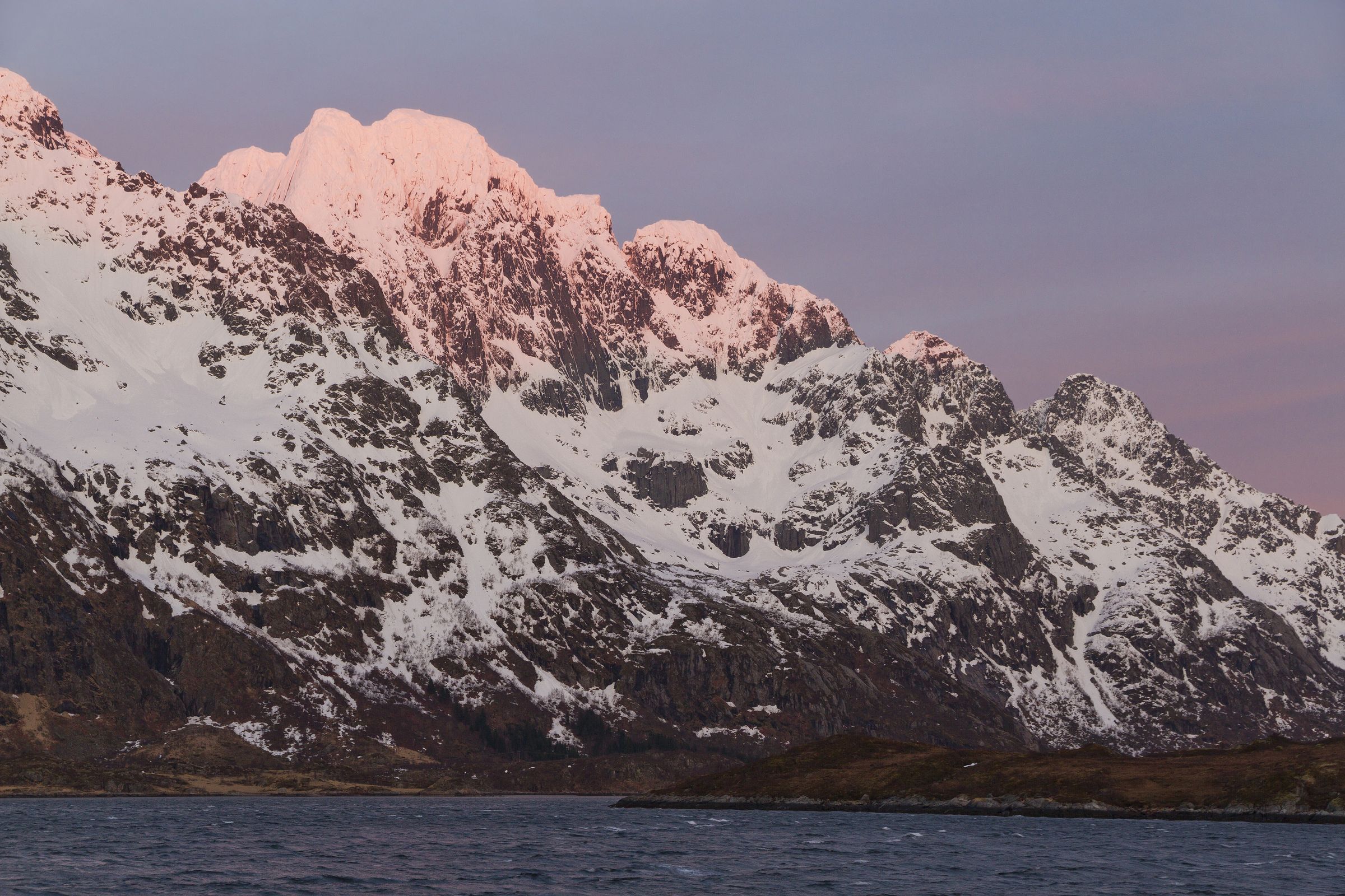 Fjord og fjell ved solnedgang med et kompass i forgrunnen